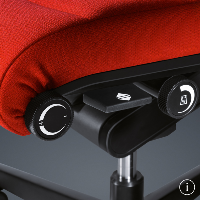 Primer plano de la palanca negra de la silla giratoria CHAMP debajo del tapizado del asiento rojo.