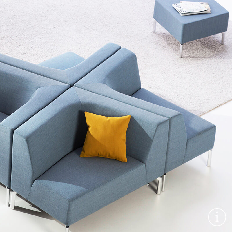 Cuatro elementos de asiento Tangram llenos de estilo con los respaldos orientados unos contra otros, en azul y cojín amarillo.
