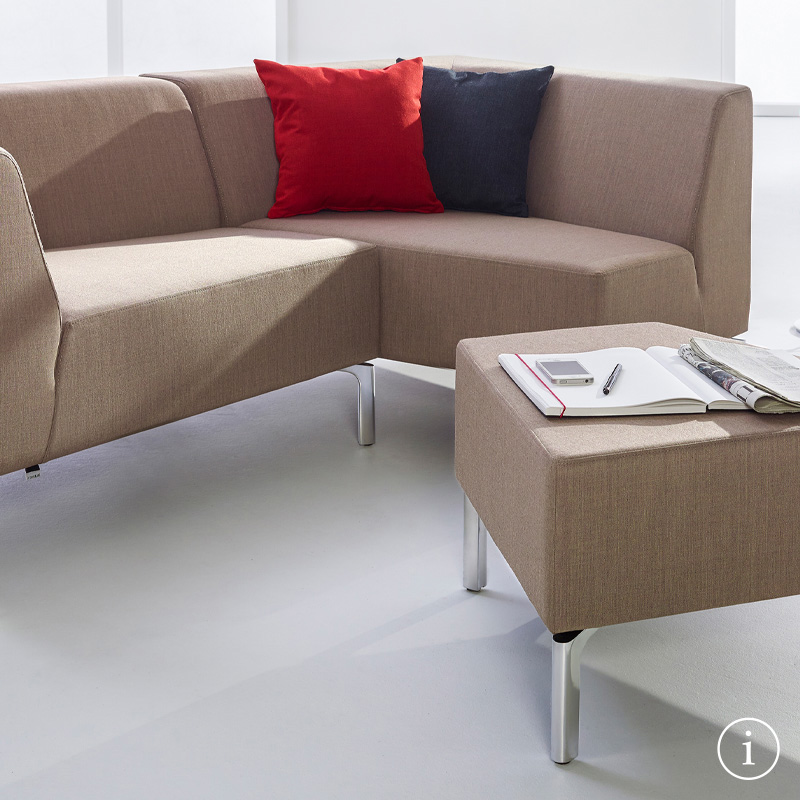 Tangram-sofa met twee modules in het bruin met twee kussens en daarvoor een functionele Tangram-sofakruk.