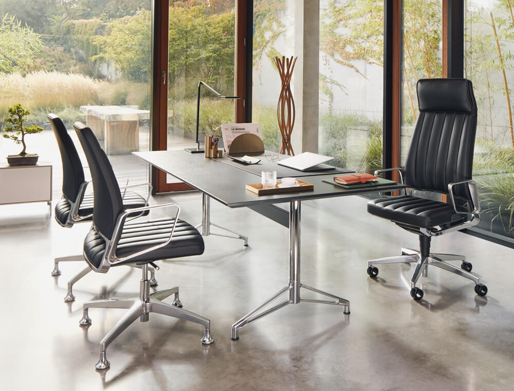 Un sillón giratorio para ejecutivos VINTAGE detrás de un escritorio con dos sillones de conferencia enfrente en un despacho de dirección con mucho estilo.