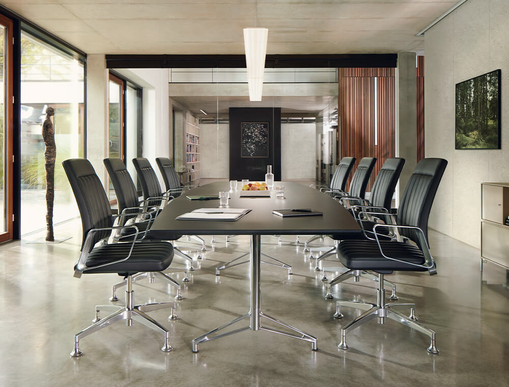 Otto sedie da conferenza VINTAGE disposte intorno a un lungo tavolo in una sala conferenze. Garantiscono una seduta attiva e dinamica durante le riunioni più lunghe.