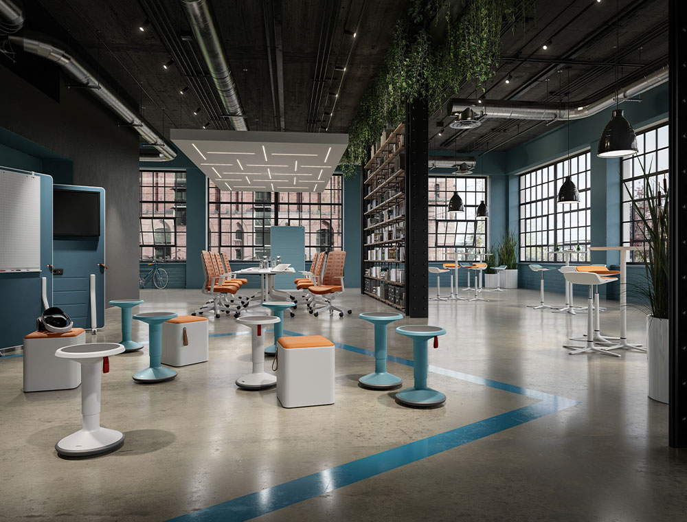 Billede af et åbent kontormiljø med syv UP-skamler i hvid og ice blue i forgrunden i en undervisningsscene. I baggrunden ses et stort bord med kontorstolene Pure i orange samt ståborde med barstolene Kinetic.